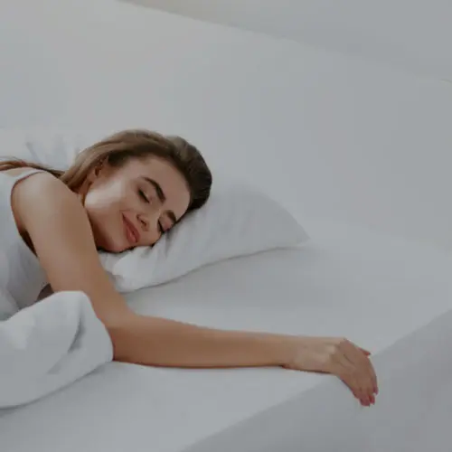 A woman sleeping on a clean white mattress